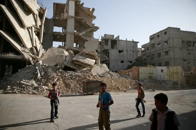 Boys walk near damaged buildings in the rebel-held besieged town of Zamalka, in the Damascus suburbs, Syria October 3, 2016. (Photo by Bassam Khabieh/Reuters)