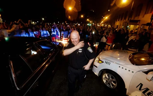 A police officer in Boston reacts to news of the arrest of Dzhokhar Tsarnaev, on April 19, 2013. (Photo by Julio Cortez/Associated Press)