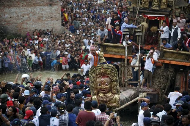 A devotee (C) directs people pulling the chariot of Rato Machhindranath through the Nakhu River during the chariot festival in Lalitpur, Nepal September 23, 2015. (Photo by Navesh Chitrakar/Reuters)