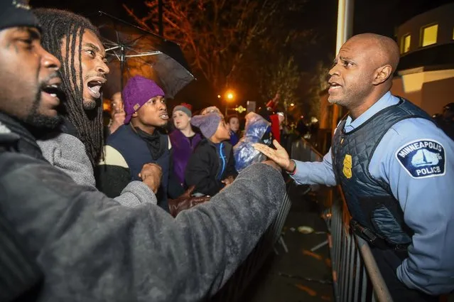 A police officer talks with demonstrators in front of a north Minneapolis police precinct during a protest in response of Sunday's shooting death of Jamar Clark by police officers in Minneapolis, Minnesota, November 18, 2015. State officials on Wednesday identified the two Minneapolis police officers involved in the fatal shooting of an unarmed black man that has sparked protests and dozens of arrests. (Photo by Craig Lassig/Reuters)