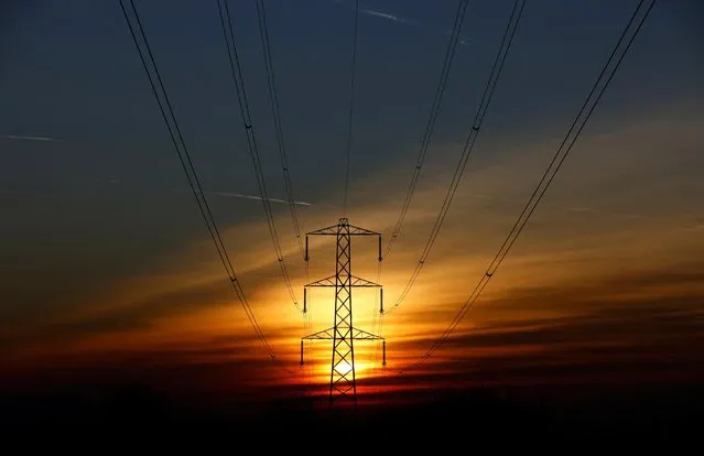 The sun sets behind an electricity pylon in Borehamwood, Britain on February 8, 2023. (Photo by Peter Cziborra/Reuters)