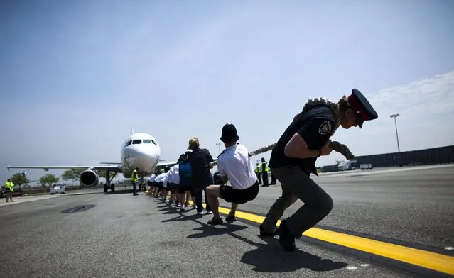 Members of the London Metropolitan Police Service tug an Airbus A320 jet for 100 feet (30.48m) during a race at John F. Kennedy International Airport in New York, May 20, 2013. The fourth annual race “Plane Pull” is a fundraising competition to benefit the charity Joining Against Cancer in Kids. (Photo by Eduardo Munoz/Reuters)