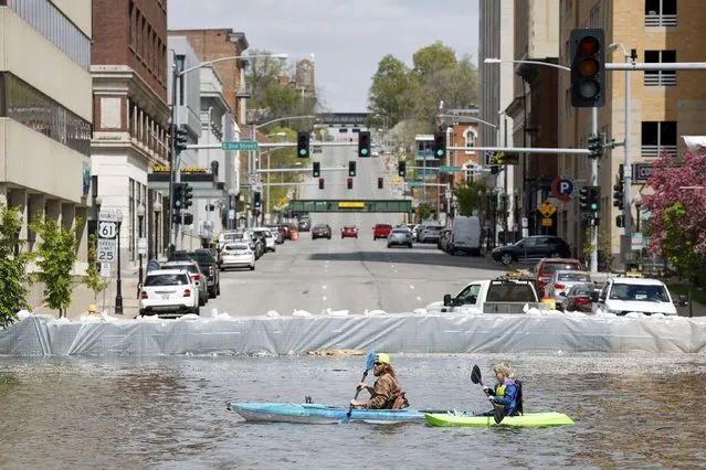 A group of kayakers paddle along River Drive along the HESCO sand barriers protecting downtown from the rising Mississippi River, Saturday, April 29, 2023, in Davenport, Iowa. The Upper Mississippi River will rise to near record-high levels as it flows through Wisconsin and Iowa. (Photo by Nikos Frazier/Quad City Times via AP Photo)