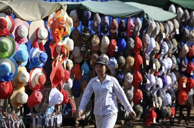 A woman walks past kiosks selling hats along a street in central Phnom Penh January 9, 2015. (Photo by Samrang Pring/Reuters)