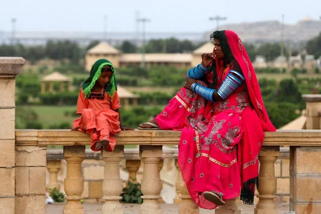 A Pakistani Hindu devotee woman and a girl sit while waiting with others for transport before leaving to pay homage at Hinglaj Mata Temple in Balochistan, outside the Shri Ratneshwar Mahadev Temple in Karachi, Pakistan on April 28, 2023. (Photo by Akhtar Soomro/Reuters)