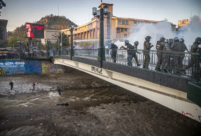 A youth lies in the Mapocho river after falling from a bridge during a police charge on protesters in Santiago, Chile, Friday September 2, 2020. The incident unleashed a wave of criticism against police for the repression during demonstrations and the government repudiated the acts of violence condemning “categorically any action that violates human rights”. The young man is in a hospital in serious but stable condition, according to the latest medical reports. (Photo by Aliosha Marquez Alvear/AP Photo)