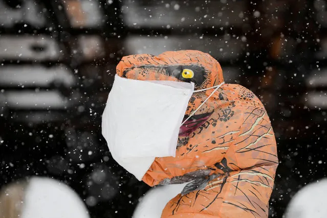 A person wearing an inflatable T-Rex costume with a mask on stands in Central Park as snow falls in Manhattan, New York City, U.S., February 7, 2021. (Photo by Andrew Kelly/Reuters)