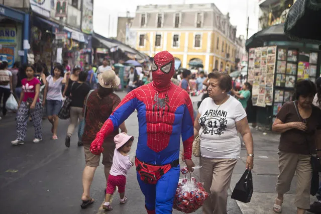 A man wearing a Spiderman costume walks outside the central market of Lima, Peru, Thursday, January 29, 2015. The man disguised as a comic strip hero is a street vender who sells toys, such as rubber balls. (Photo by Esteban Felix/AP Photo)