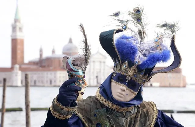 A masked reveller poses in front of St. Mark's square during the first day of carnival, in Venice February 1, 2015. (Photo by Stefano Rellandini/Reuters)