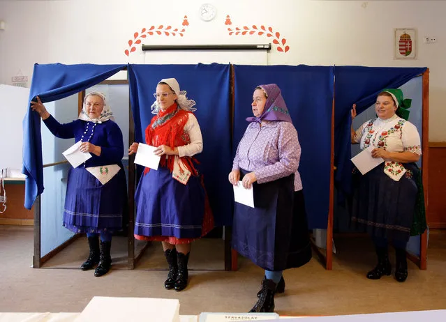 Women in traditional Hungarian dresses leave polling booths and prepare to cast their ballots at a polling station in a school in Veresegyhaz, some 30kms east of Budapest, on April 3, 2022, during the general election. Long-time nationalist Hungarian Prime Minister Viktor Orban faces a united opposition for the first time as he goes head-to-head in general elections against conservative politician Peter Marki-Zay. (Photo by Peter Kohalmi/AFP Photo)