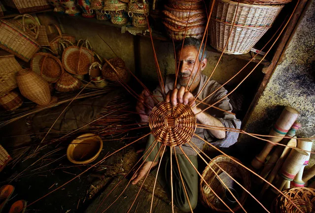 A craftsman weaves a basket made from willow twigs at his workshop on the outskirts of Srinagar, July 19, 2018. (Photo by Danish Ismail/Reuters)