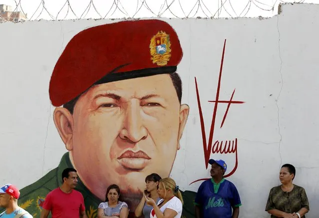 Supporters of Venezuela's President Nicolas Maduro stand in front of a mural depicting Venezuela's late President Hugo Chavez some streets away from the building housing the National Assembly in Caracas, January 5, 2016. (Photo by Christian Veron/Reuters)