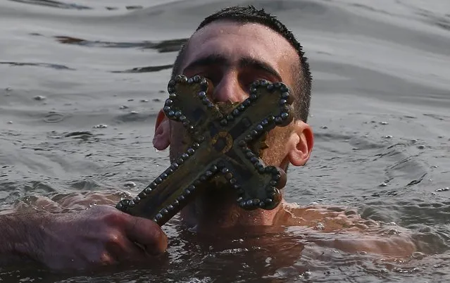 Greek Orthodox faithful Nikolas Solis, 28, a pilgrim from Agrinio of Greece, kisses a wooden crucifix in the Golden Horn in Istanbul, Turkey, January 6, 2016. (Photo by Murad Sezer/Reuters)