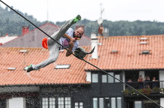 A participant falls into the water after picking up a false goose from a rope during the celebration of the traditional Goose Day local competition in Lekeitio, Vizcaya, Spain, 05 September 2018. During this event, a geese are hanged from a rope in the middle of the harbour and participants have to grab them and jump into the water. The competition is held every 5th September and is attended by thousands of people. This edition has been the first one held using false geese made of rubber. (Photo by Miguel Tona/EPA/EFE)