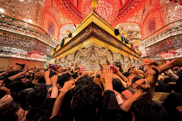 Shiite Muslim devotees reach to receive a blessing from the tomb of Imam Hussein, the Prophet Mohammed's grandson, at the Imam's shrine in Iraq's central holy city of Karbala on September 6, 2023, during the Arbaeen religious festival commemorating his seventh century killing. (Photo by Hussein Faleh/AFP Photo)
