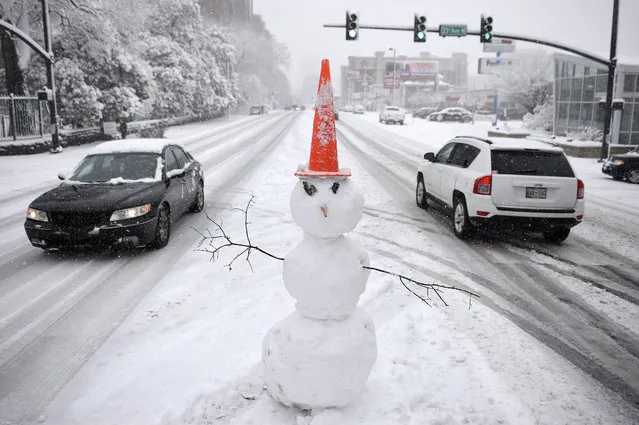 A snowman stands on a traffic median. Friday, January 22, 2016, in Nashville, Tenn. A blizzard menacing the Eastern United States started dumping snow in Virginia, Tennessee and other parts of the South on Friday as millions of people in the storm's path prepared for icy roads, possible power outages and other treacherous conditions. (Photo by Andrew Nelles/The Tennessean via AP Photo)