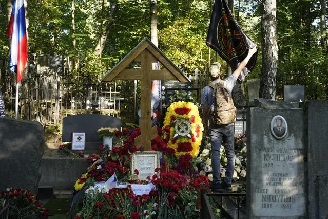 A man straightens a flag of the Wagner private military contractor at the grave of Yevgeny Prigozhin at Porokhovskoye Cemetery in St. Petersburg, Russia, on Friday, Sept. 22, 2023. Prigozhin, the head of Wagner, was killed on August 23 when a private jet carrying him and his top lieutenants crashed while flying from Moscow to St. Petersburg, killing all 10 people aboard. (Photo by Dmitri Lovetsky/AP Photo)