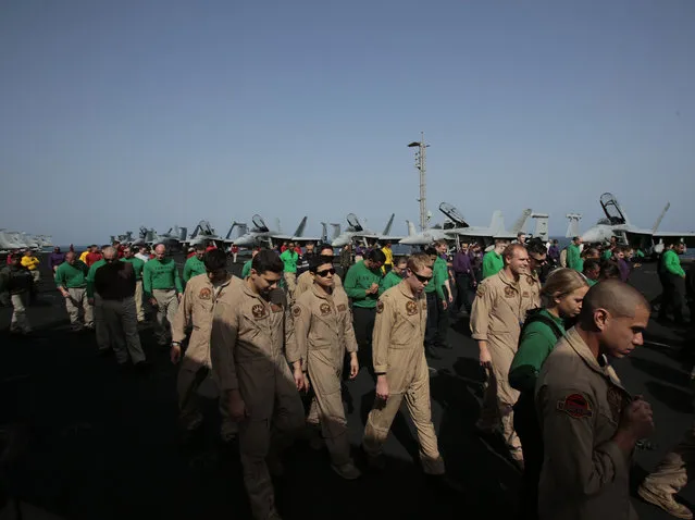 U.S. sailors and pilots walk on the flight deck, checking for any debris, aboard the USS Carl Vinson aircraft carrier in the Persian Gulf, Thursday, March 19, 2015. (Photo by Hasan Jamali/AP Photo)