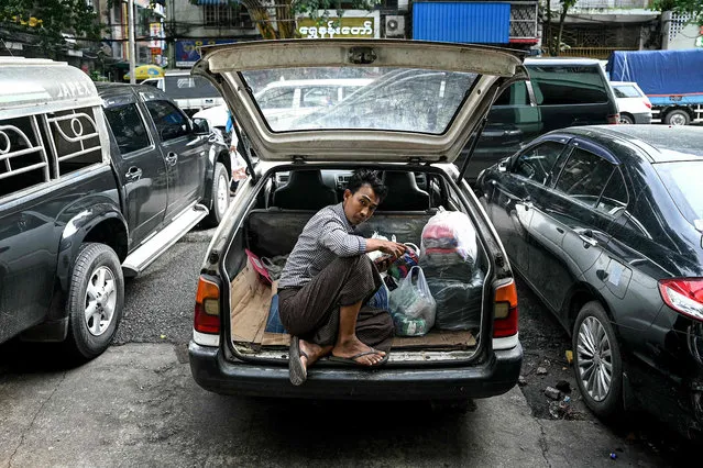 A man sits at the back of his car in the city centre of Yangon on September 15, 2023. (Photo by Sai Aung Main/AFP Photo)