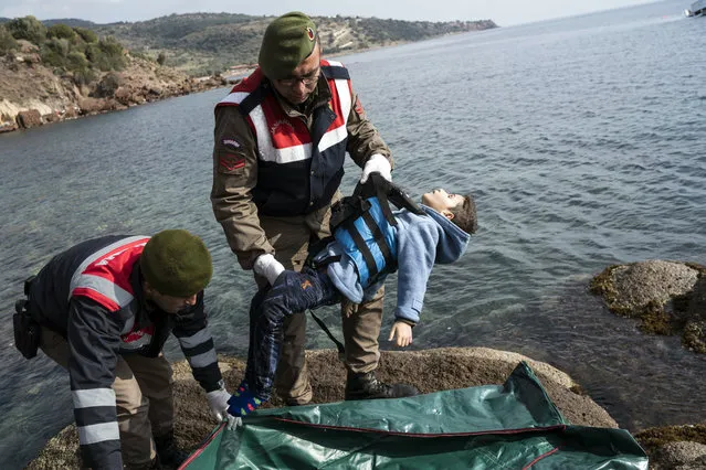 Turkish paramilitary police officer holds the dead body of a migrant boy from the shoreline near the Aegean town of Ayvacik, Canakkale, Turkey, Saturday, January 30, 2016. (Photo by Halit Onur Sandal/AP Photo)