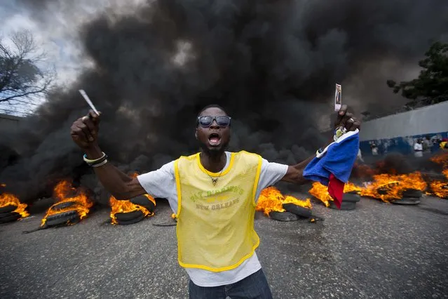An anti-government demonstrator holds up a picture of former president Jean Bertrand Aristide as he demand the president's resignation in Port-au-Prince, Haiti, Saturday, February 6, 2016. Top Haitian leaders negotiated an agreement to install a short-term provisional government less than 24 hours before President Michel Martelly was scheduled to step down, an official with the Organization of American States and local authorities announced Saturday. (Photo by Dieu Nalio Chery/AP Photo)