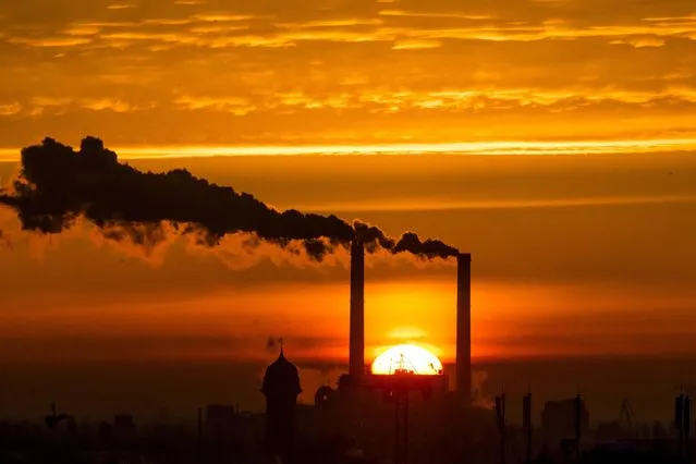 Sun rises behind billowing chimneys of power station in Berlin, on November 26, 2013. (Photo by Thomas Peter/Reuters)