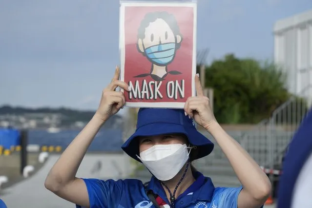 In this August 1, 2021, file photo, Olympic volunteer Reimi Kusunoki holds up a sign at the Enoshima yacht harbor during the 2020 Summer Olympics in Fujisawa, Japan. Tokyo Olympians are exercising extraordinary discipline against the coronavirus. They are sealed off in a sanitary bubble that has made competition possible but is also squeezing a lot of fun from their Olympic experience. (Photo by Gregorio Borgia/AP Photo/File)