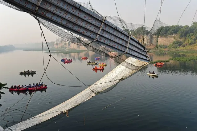 Rescue personnel conduct search operations after a bridge across the river Machchhu collapsed at Morbi in India's Gujarat state on October 31, 2022. At least 130 people were killed in India after a colonial-era pedestrian bridge collapsed, sending scores of people tumbling into the river below, police said on October 31. (Photo by Sam Panthaky/AFP Photo)