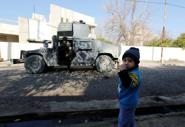 A child stands near a military vehicle of Iraqi Counter Terrorism Forces (ICTF) during an operation to clear the al-Andalus district of Islamic State militants, in Mosul, Iraq, January 16, 2017. (Photo by Muhammad Hamed/Reuters)