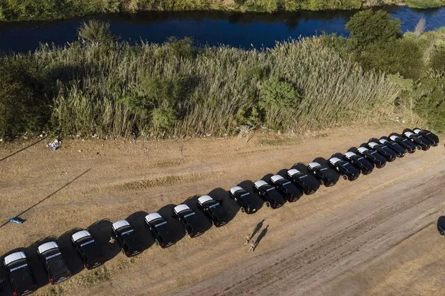 A line of Texas Department of Safety vehicles lines the bank of the Rio Grande near an encampment of migrants, many from Haiti, Wednesday, September 22, 2021, in Del Rio, Texas. (Photo by Julio Cortez/AP Photo)