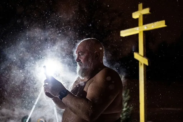 A man uses his mobile phone after taking a dip in the icy water of a pond during Orthodox Epiphany celebrations in Moscow, Russia on January 19, 2024. (Photo by Maxim Shemetov/Reuters)