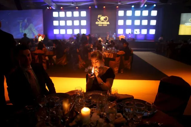 Cigar dealer Nadine Meier from Switzerland lights a cigar during the gala dinner for the closing of the XVIII Habanos Festival in Havana, March 4, 2016. (Photo by Alexandre Meneghini/Reuters)