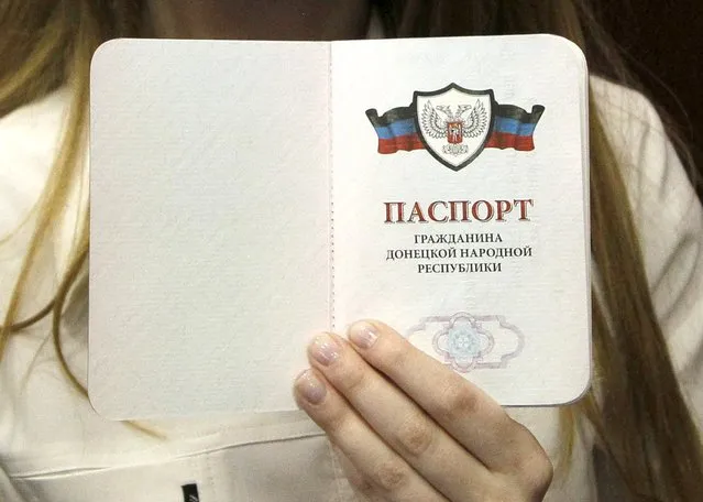A woman displays her passport after receiving it during a ceremony to issue the first passports of the self-proclaimed Donetsk People's Republic to residents in Donetsk, Ukraine, March 16, 2016. The words read “Passport of a citizen of the Donetsk People's Republic”. (Photo by Alexander Ermochenko/Reuters)