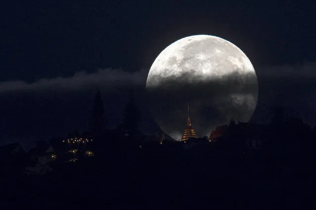 The supermoon is partly covered by clouds as it sets behind Wat Phrathat Doi Suthep in the northern capital of Chiang Mai, Thailand, November 15, 2016. (Photo by Athit Perawongmetha/Reuters)