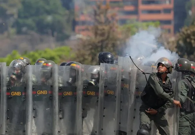 A member of the National Guard throws an object towards opposition supporters during a rally against the government of Venezuela's President Nicolas Maduro and to commemorate May Day in Caracas, May 1, 2019. (Photo by Manaure Quintero/Reuters)