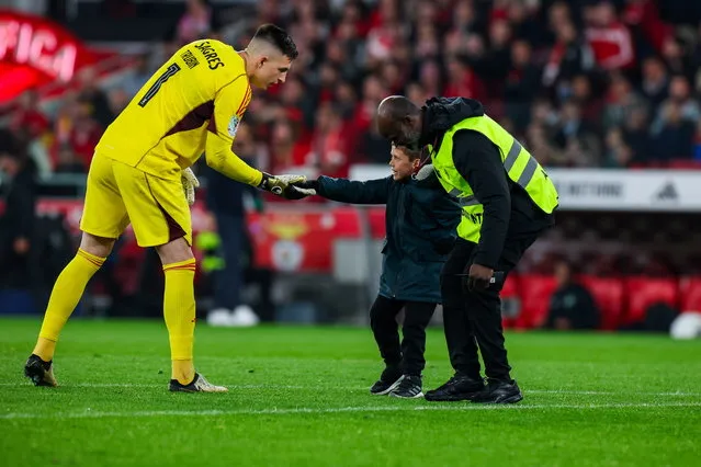 Benfica player Anatolii Trubin shake hands with a child who invades the field during the Portuguese the Portugal Soccer Cup second leg semi-final match between Benfica and Sporting held at Luz Stadium, in Lisbon, Portugal, 02 April 2024. (Photo by Jose Sena Goulao/EPA)