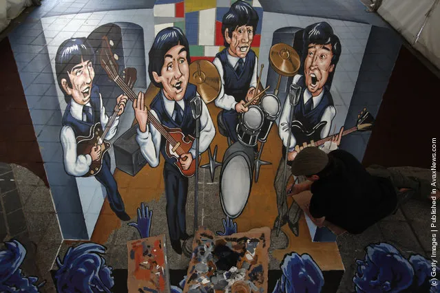 Street artist Juandres Vera puts the finishing touches to a giant 3d pavement mural of The Beatles