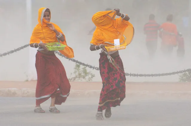 Indian women adjust their clothes during a sudden dust storm in New Delhi, India, 19 May 2015. (Photo by EPA/Stringer)