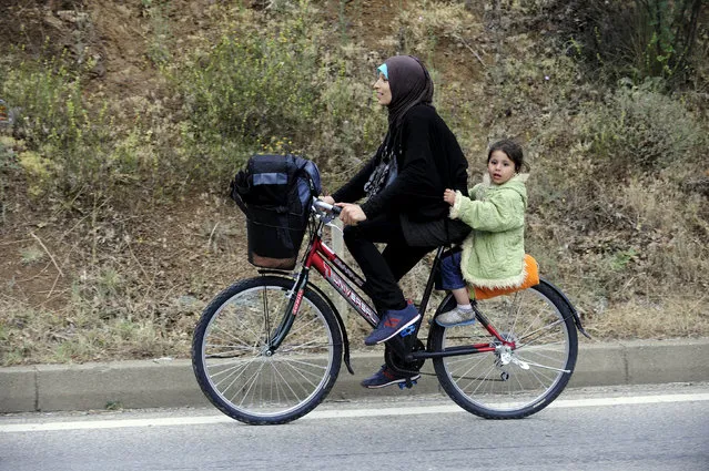 Migrants from Syria ride their bicycles near the Greek border in Macedonia June 17, 2015.  Hungary announced plans on Wednesday to build a four-metre-high fence along its border with Serbia to stem the flow of illegal migrants. Tens of thousands of migrants enter Europe through the Balkans from the Middle East and Africa. REUTERS/Ognen Teofilovski 