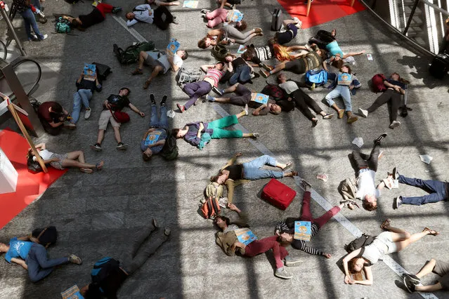 Environmental activists lay down, chanting slogans to urge people not to fly, in a hall at Zurich Airport, Switzerland on July 13, 2019. Dozens of climate activists staged a peaceful protest at Zurich Airport on Saturday, denouncing the negative impact of air travel on the environment. They lay on the ground briefly and then walked along the shopping area distributing flyers. (Photo by Arnd Wiegmann/Reuters)