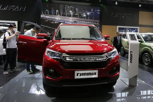 Journalists examine the Chinese automaker Lifan new X70 SUV on display at the Beijing International Automotive Exhibition in Beijing, Monday, April 25, 2016. (Photo by Andy Wong/AP Photo)