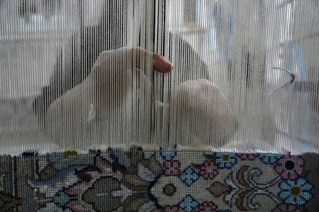 An Iranian woman weaves a carpet at a workshop in the city of Kashan, about 152 miles (245 km) south of the capital Tehran, Iran, Tuesday, April 30, 2024. (Photo by Vahid Salemi/AP Photo)