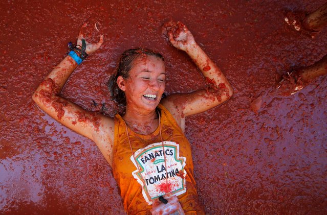 A reveler lies in tomato pulp during the annual “La Tomatina” tomato food fight festival in Bunol, near Valencia, Spain on August 28, 2019. (Photo by Heino Kalis/Reuters)