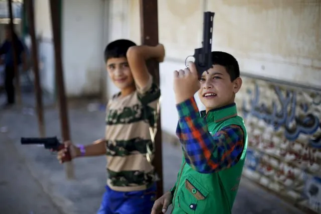 Syrian refugee children play with toy guns during the first day of Eid al-Fitr, marking the end of the holy month of Ramadan, at the Al-Zaatari refugee camp in Mafraq, Jordan, near the border with Syria, July 17, 2015. Eid al-Fitr marks the end of the Muslim holy month of Ramadan. (Photo by Muhammad Hamed/Reuters)