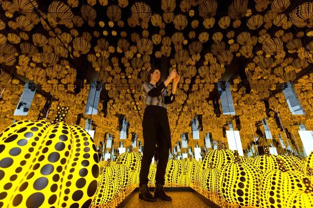 A gallery assistant poses for as photograph with an art installation entitled “All the Eternal Love I Have for the Pumpkins”, 2016, by Japanese artist Yayoi Kusama, at the Victoria Miro gallery in London on May 26, 2016. The exhibition is set to run from May 25 to July 30. (Photo by Justin Tallis/AFP Photo)