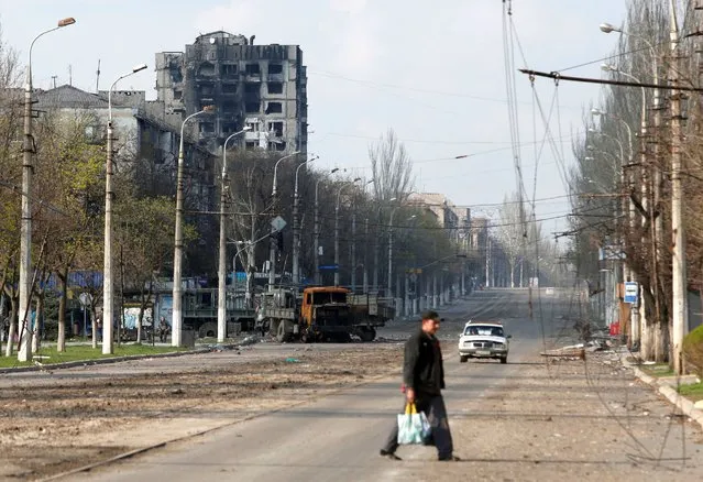 A local resident crosses a street damaged during Ukraine-Russia conflict in the southern port city of Mariupol, Ukraine on April 15, 2022. (Photo by Alexander Ermochenko/Reuters)