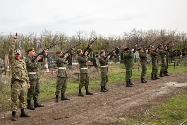 Servicemen of the People's Militia of the Lugansk People's Republic fire a salute during a farewell ceremony for Lt Col Mikhail Kishchik, commander of the 11th territorial defence battalion, codenamed Chechen, on the Avenue of Glory in Lugansk, Lugansk People's Republic on April 19, 2022. Kishchik was killed while breaking out of encirclement outside Kreminna, 95km northwest of Lugansk. (Photo by Alexander Reka/TASS)