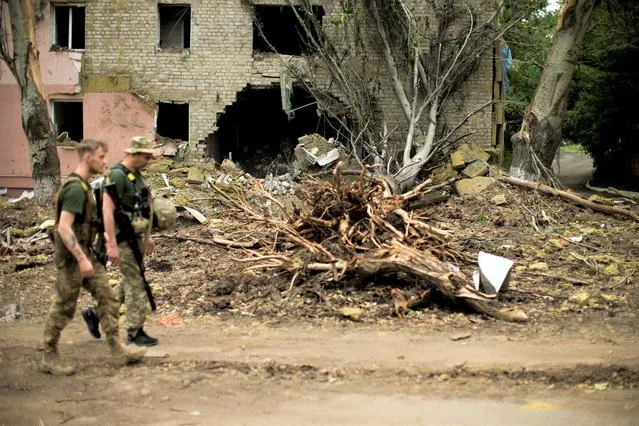 Ukrainian servicemen walk past a building heavily damaged in a Russian bombing in Bakhmut, eastern Ukraine, eastern Ukraine, Saturday, May 28, 2022. (Photo by Francisco Seco/AP Photo)
