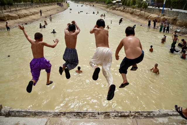 Afghan boys jump into a canal on the outskirts of Kandahar province on July 30, 2024. (Photo by Sanaullah Seiam/AFP Photo)