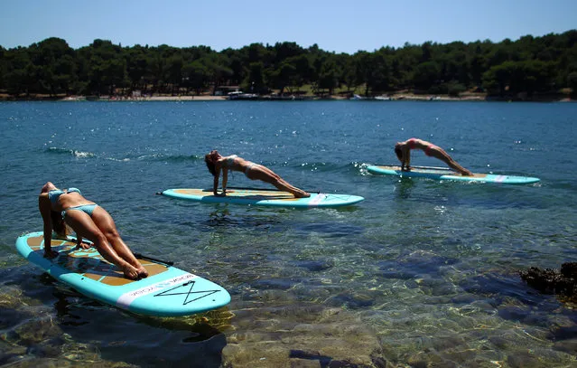 People practise standup paddleboard yoga, or SUP yoga, on the Adriatic coast in Verudela, Croatia July 10, 2017. (Photo by Antonio Bronic/Reuters)